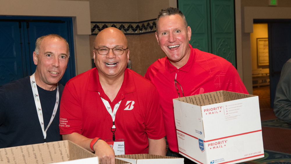 Derek Sanders, Region Operations Manager; Mark Delacruz, HRBP; and Joe Venezia pack a box  for the troops as part of the BSRO give back program at the 2020 National Leadership Conference 