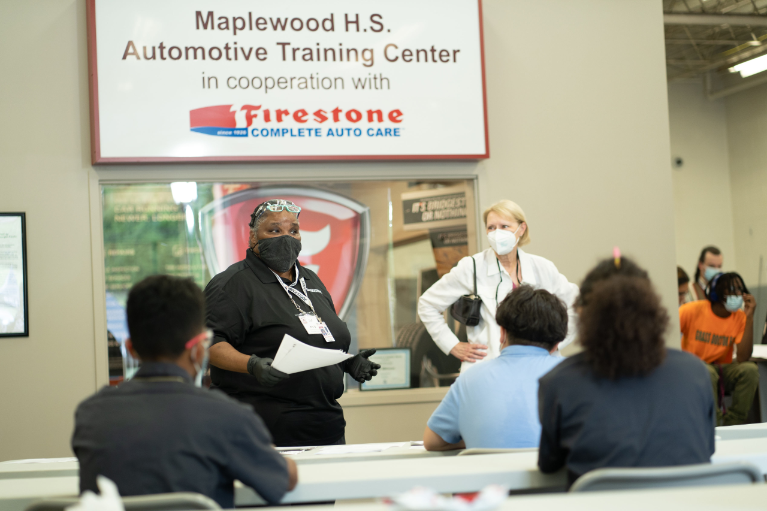 Ms. TJ Williams, Auto Training Center instructor and part-time Bridgestone employee, and Chris Karbowiak, retired Executive Vice President for Bridgestone Americas, welcome the Auto Training Center students back to the classroom