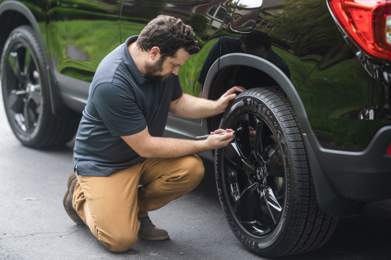 Driver Checking Tire Pressure