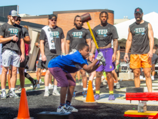 Local Boys & Girls Club kid shows his strength as Tight Ends coach from the sidelines.