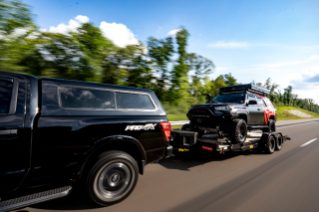 Nissan Titan outfitted with Firestone Airide towing Toyota 4Runner on the highway.