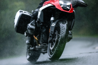 Bridgestone BATTLAX ADVENTURE A42 motorcycle tire shown in wet road conditions, highlighting its on-road adventure application.
