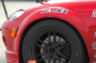 Close-up of a red competition car equipped with a Bridgestone Potenza tire and Potenza RE-71RZ branding.